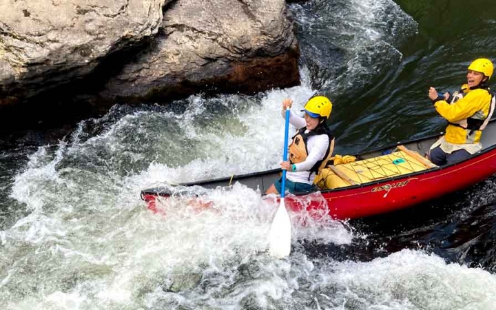 two gap year students paddle a canoe through whitewater on an outward bound expedition in north carolina 